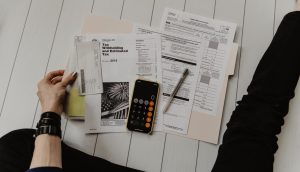 Photo by Kelly Sikkema person holding paper near pen and calculator